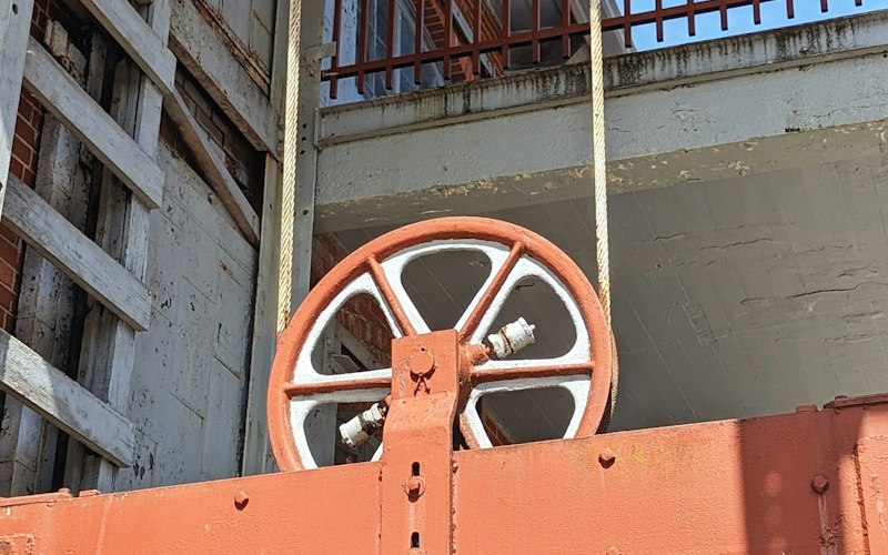 Orange hoisting assembly suspended from a steel beam