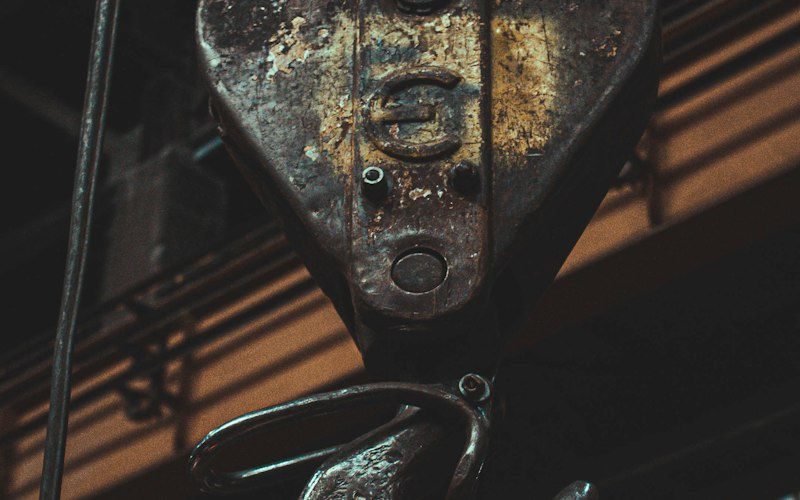 Weathered crane hook and pulley block in a heavy-duty shop