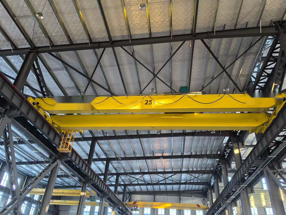Yellow double-girder overhead crane with maintenance platform in a steel workshop